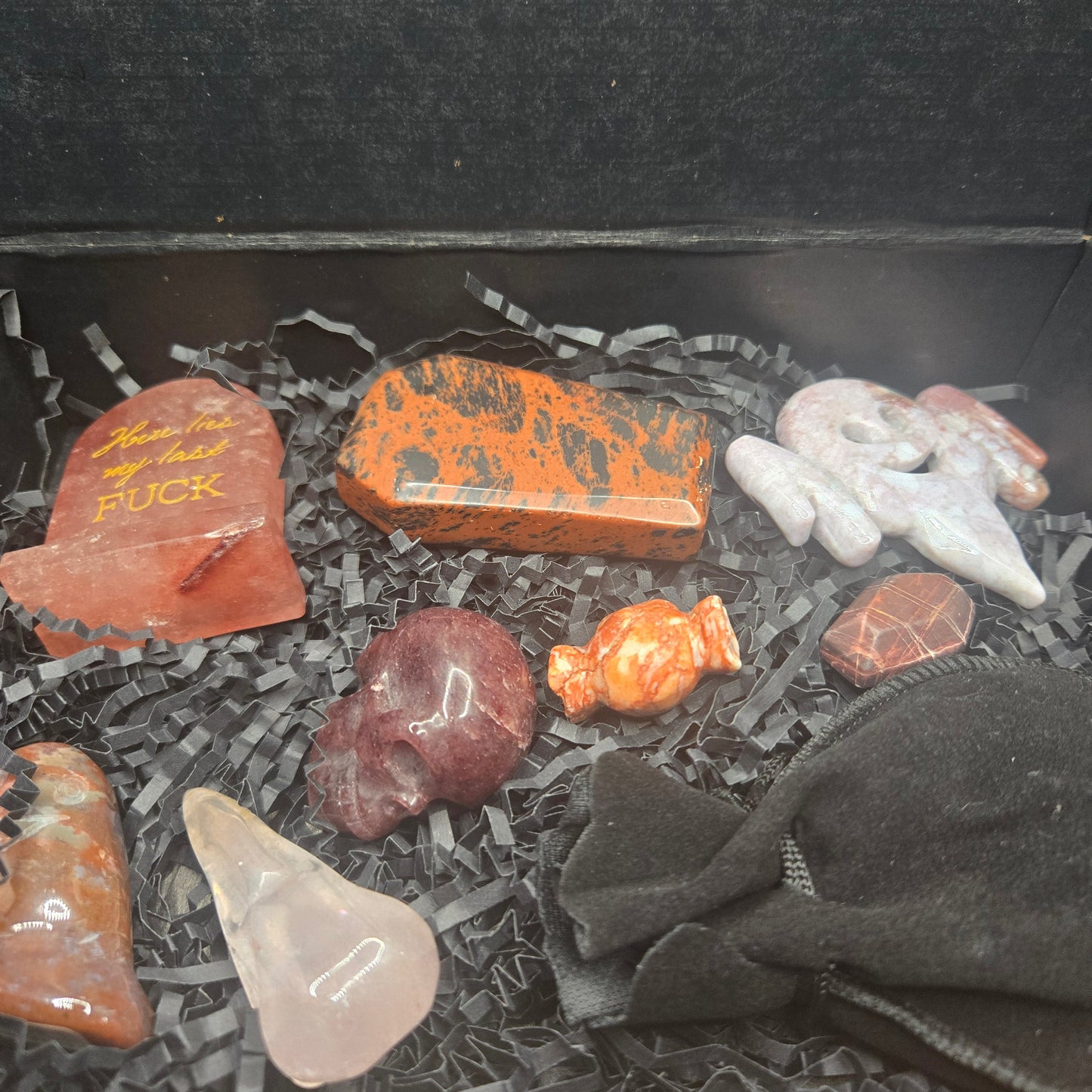 Collection of various stones and crystals on a dark surface with a black cloth.