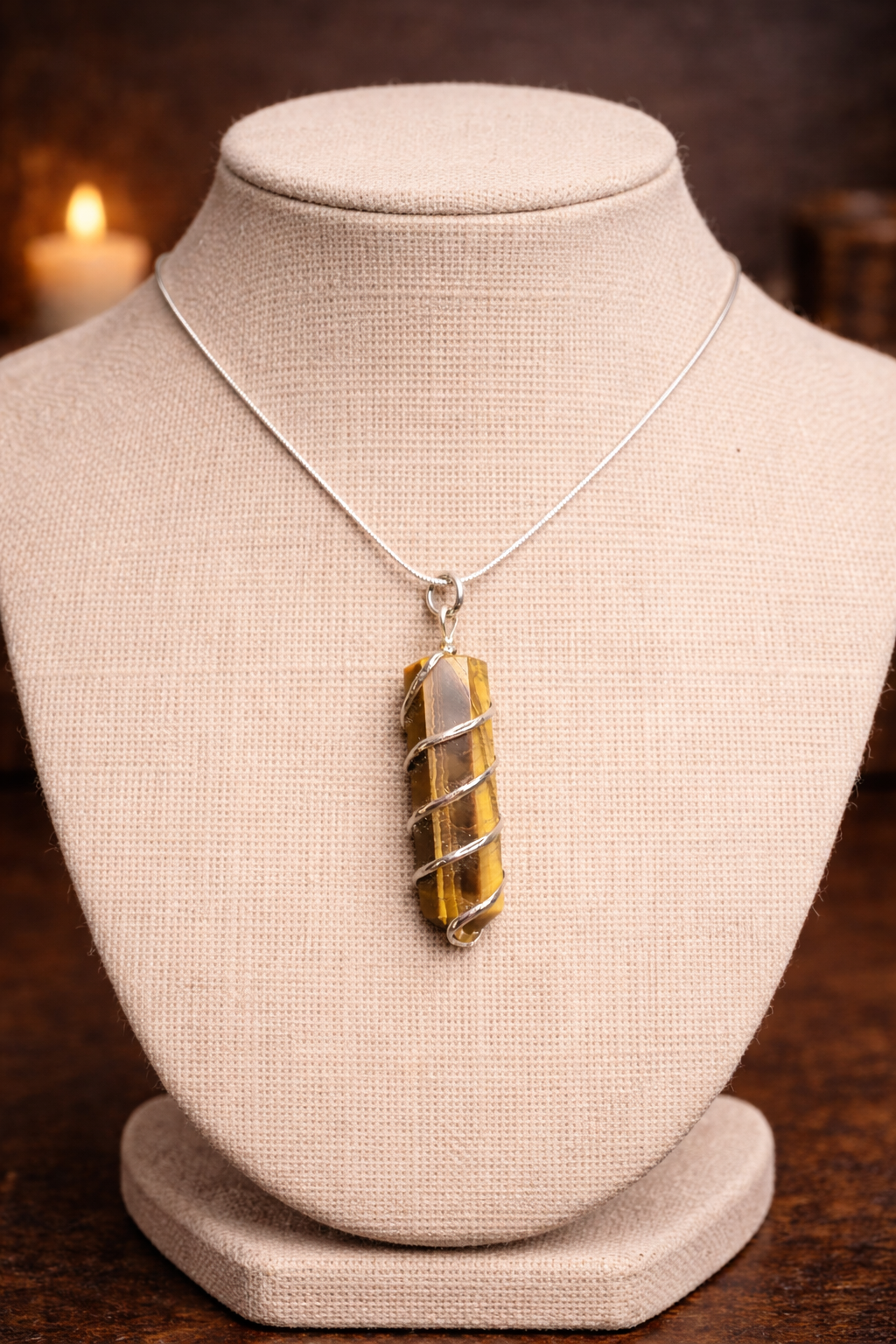 Necklace with a tiger's eye pendant on a mannequin bust against a dark background